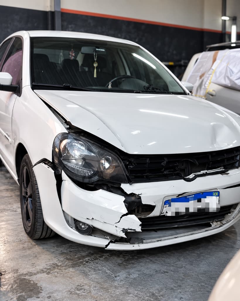 Volkswagen Polo com para-choque frontal destruído e capô amassado após colisão